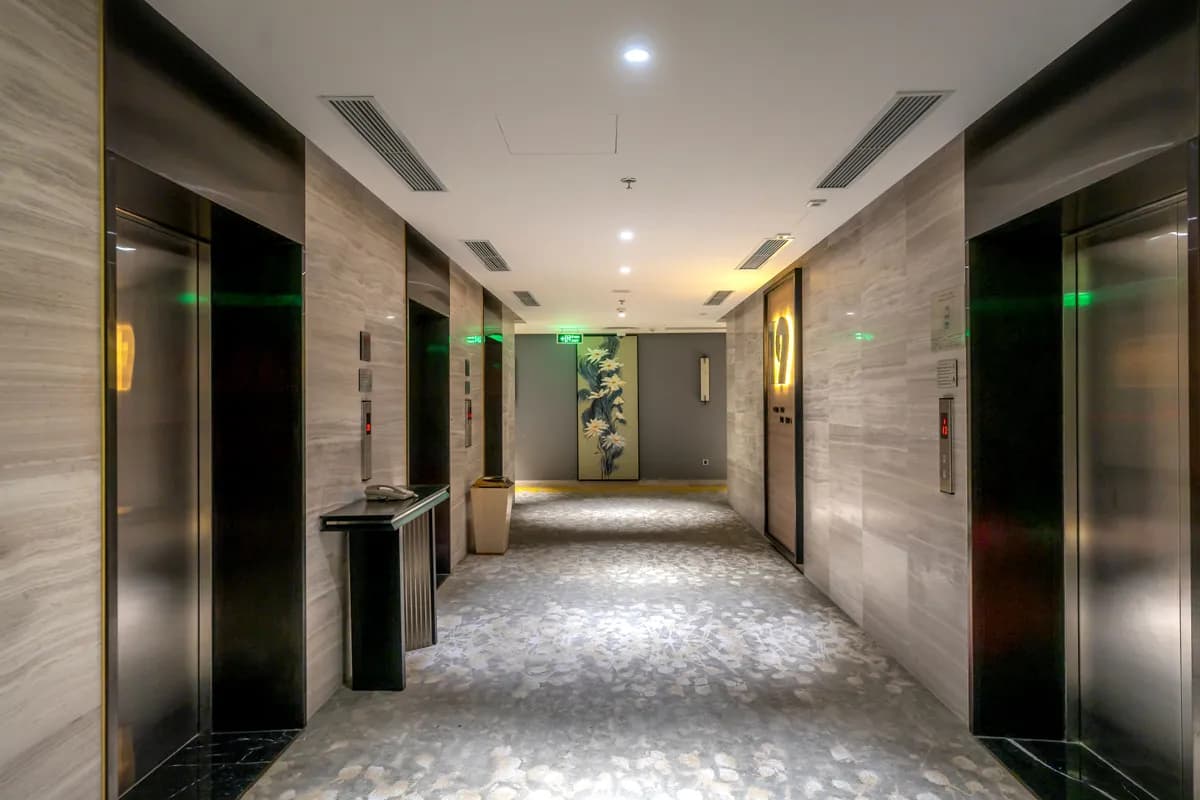 BookNoFees Beispielbild: Hotelflur mit Aufzügen und grauem Teppichboden