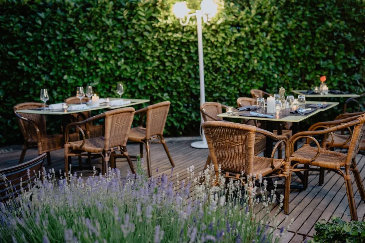 BookNoFees-voorbeeldfoto: Gedekte tafels en rieten stoelen op een terras naast lavendel