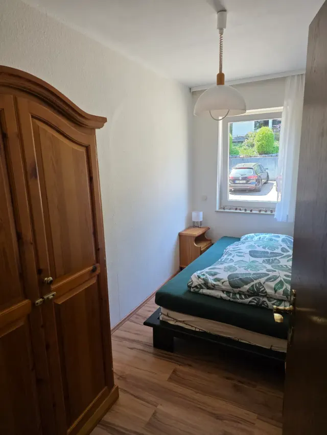 BookNoFees: Ferienwohnung in Willingen, Hessen, Deutschland – Schlafzimmer mit Einzelbett, Kleiderschrank aus Holz und Fenster mit Blick auf die Straße