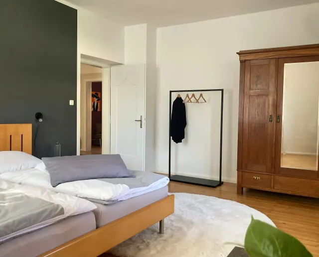 BookNoFees: Ferienwohnung in Friedberg, Bayern, Deutschland – Schlafzimmer mit Doppelbett, Kleiderschrank aus Holz und Kleiderständer mit Kleiderbügeln