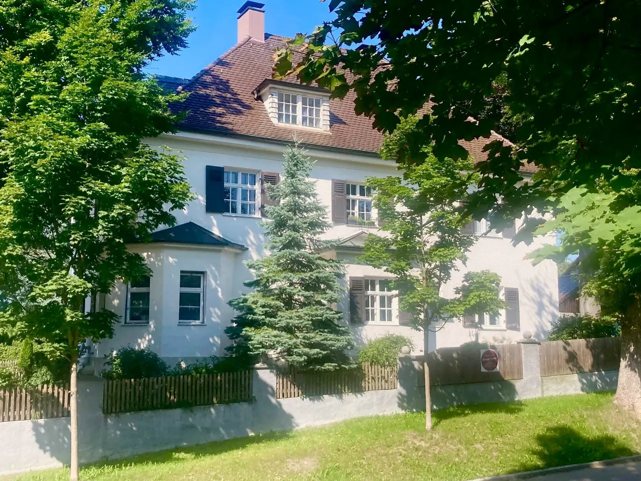 BookNoFees: Ferienwohnung in Friedberg, Bayern, Deutschland – Außenansicht eines weißen Hauses mit braunem Dach und Fensterläden, umgeben von Bäumen