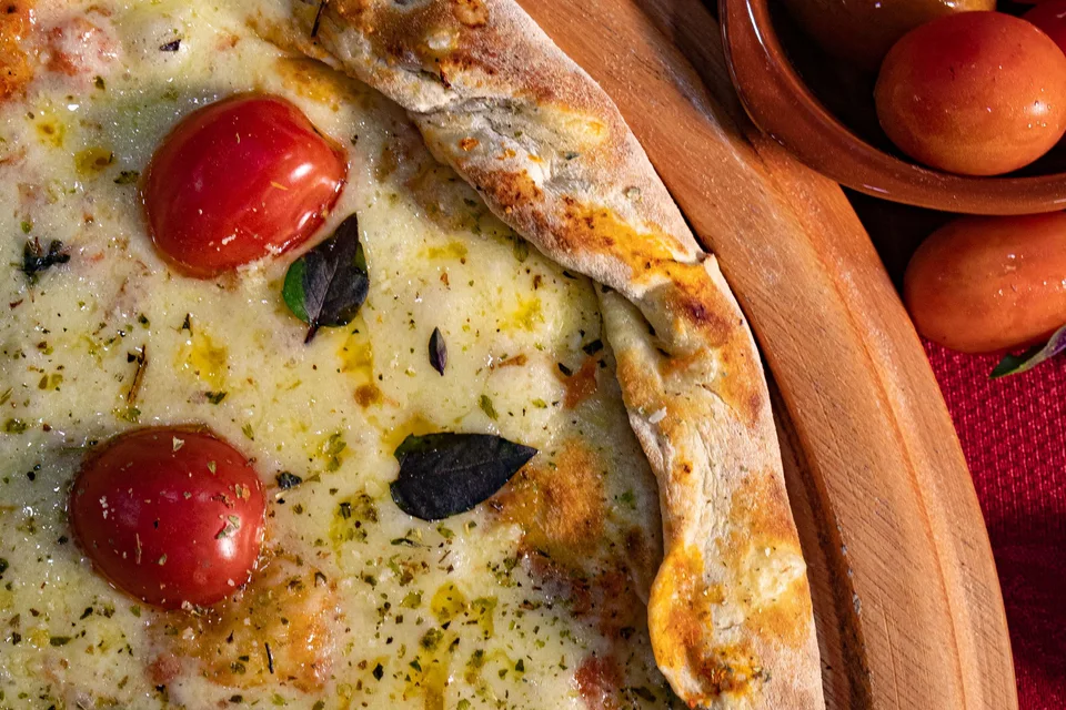BookNoFees: Photo d’illustration : Pizza au fromage garnie de tomates cerises