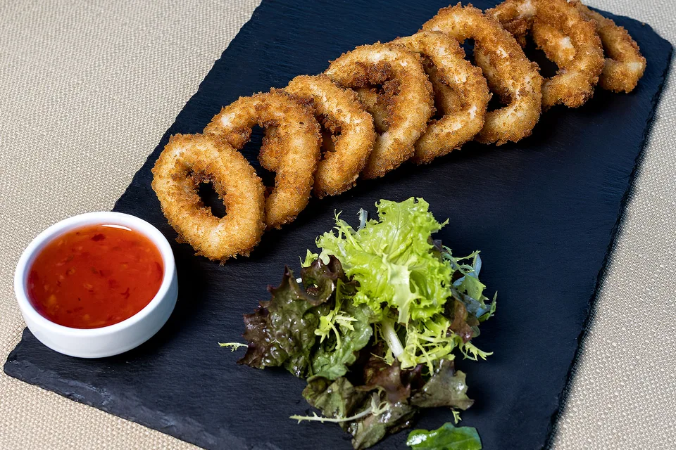 BookNoFees: Photo d’illustration : Anneaux de calamars frits accompagnés d'une salade et d'une sauce pour tremper