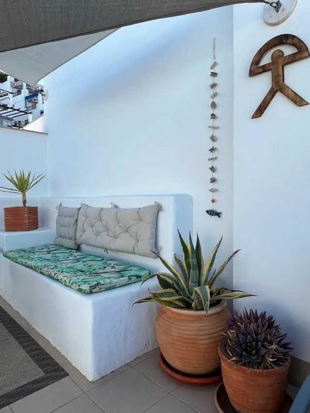 BookNoFees : location de vacances à Mojácar, Espagne – un canapé blanc dans une pièce agrémentée de plantes en pot, dans le nouvel appartement-terrasse « Cozy » de Cantal Homes à Mojácar