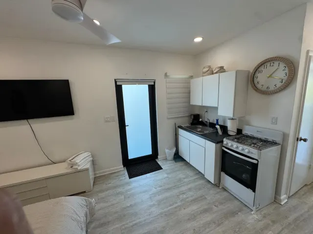 BookNoFees : location de vacances à Cutler Bay, États-Unis – Cuisine de studio avec des placards blancs, une cuisinière à gaz, une horloge murale et une porte vitrée
