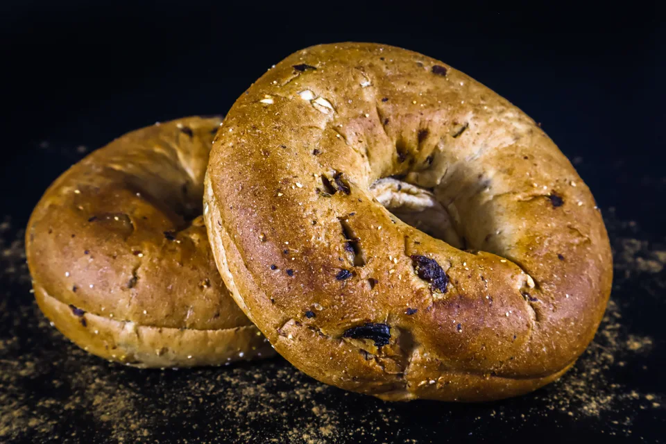 BookNoFees: Voorbeeldfoto: Twee goudbruine bagels op een donkere achtergrond