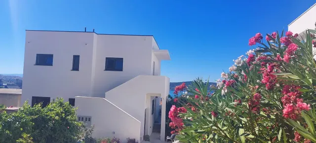 BookNoFees: vakantiehuis in Kaštel Sućurac, Split – Buitenkant van een wit vakantiehuis met een buitentrap en roze bloeiende struiken