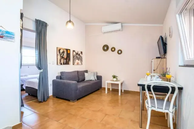 BookNoFees: vakantiehuis in Vir, Aan, Kroatië – Woonkamer met grijze bank, eettafel en aan de muur bevestigde tv