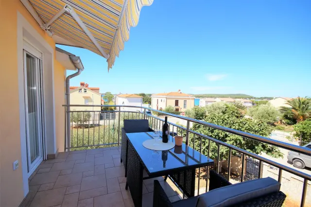 BookNoFees: vakantiehuis in Medulin – Balkon met tafel, stoelen, een wijnfles en een gestreept zonnescherm, met uitzicht op de stad