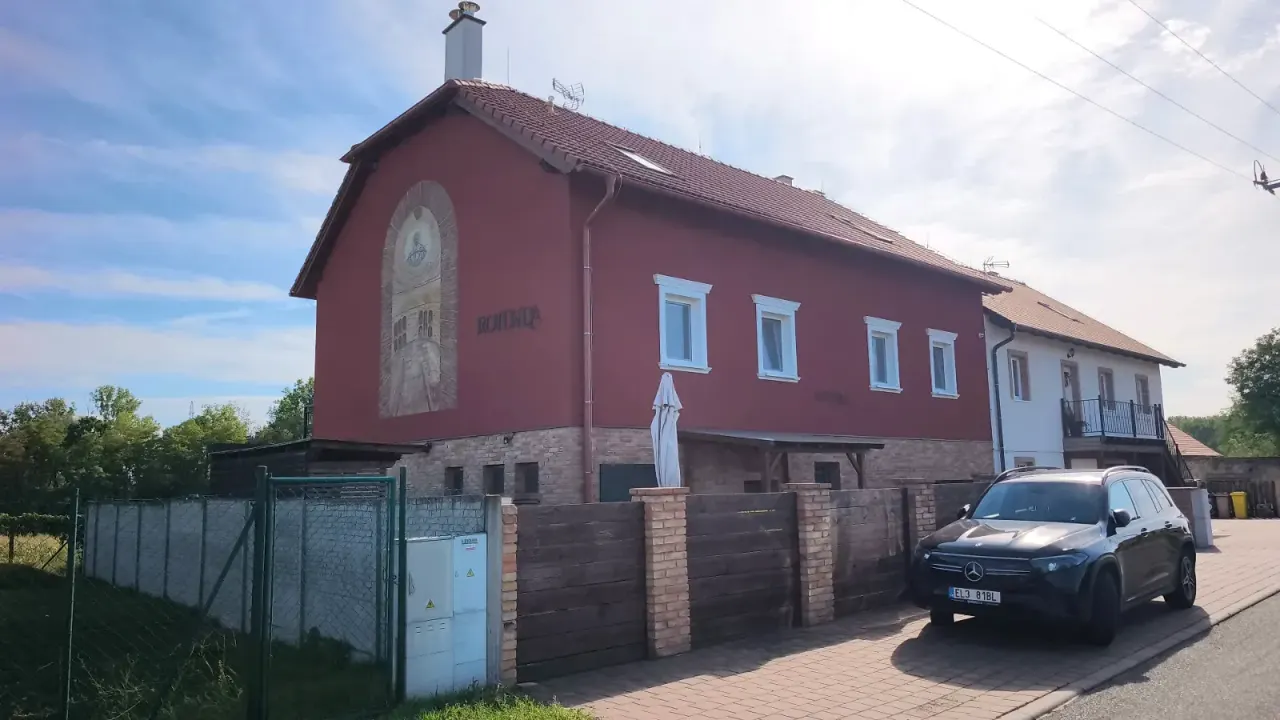 BookNoFees: vakantiehuis in Jevišovka, Regio Zuid-Moravië, Tsjechië – Buitenkant van een rood gebouw van twee verdiepingen met een muurschildering, een houten hek en een geparkeerde auto