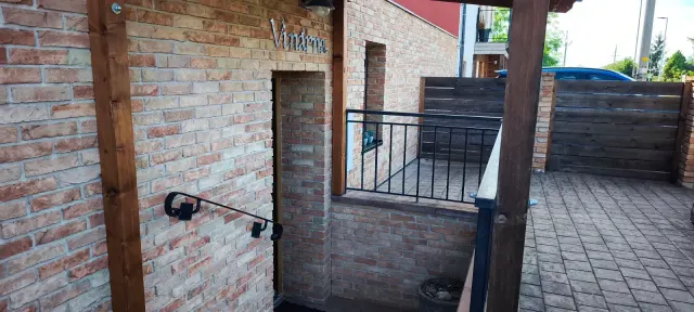 BookNoFees: vakantiehuis in Jevišovka, Regio Zuid-Moravië, Tsjechië – Buiteningang van een bakstenen gebouw met houten pilaren en een metalen leuning