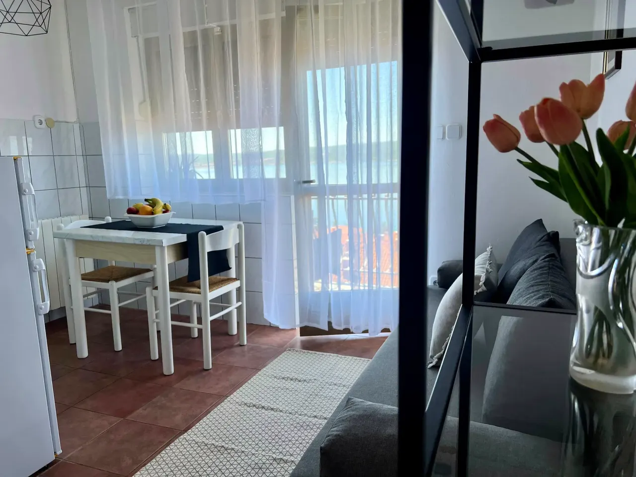 BookNoFees: vakantiehuis in Crikvenica, Provincie Primorje-Gorski Kotar, Kroatië – Keuken en woonruimte met eettafel, bank en balkondeur met vitrages