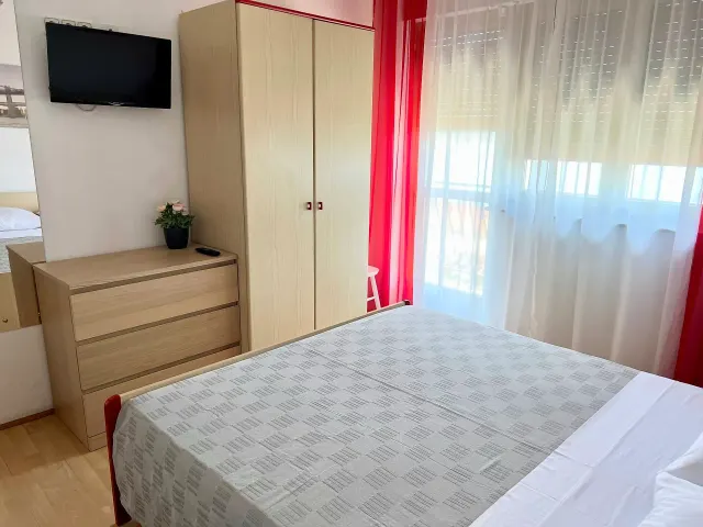 BookNoFees: vakantiehuis in Crikvenica, Provincie Primorje-Gorski Kotar, Kroatië – Slaapkamer met tweepersoonsbed, kledingkast, dressoir, aan de muur bevestigde tv en rode gordijnen