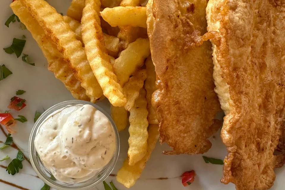 BookNoFees: Beispielfoto: Panierte Fischfilets mit wellenförmig geschnittenen Pommes frites und einer kleinen Schale Soße
