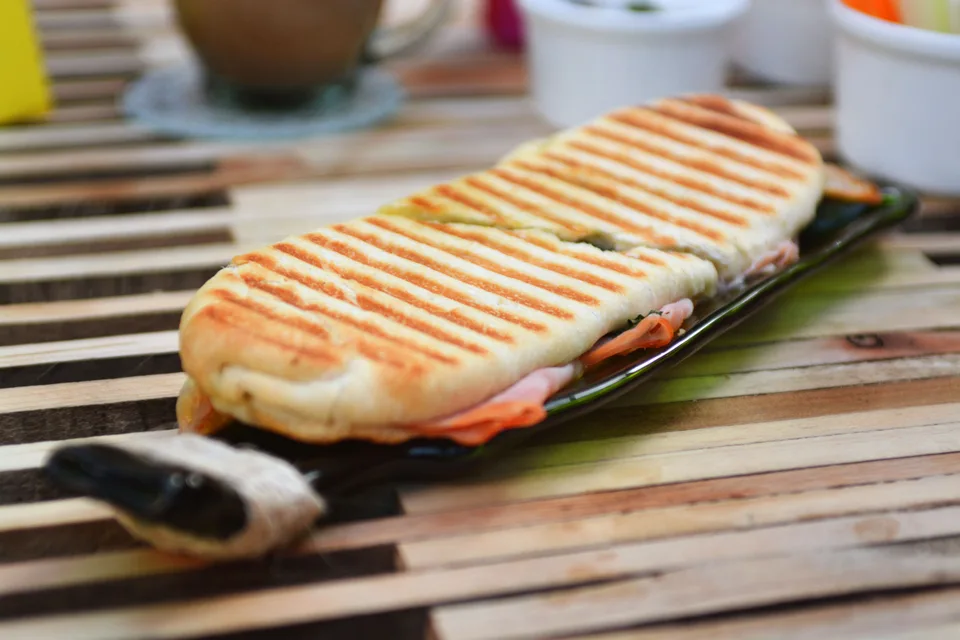 Photo d’illustration : Un panini grillé présentant des marques de grillade, servi sur une assiette foncée