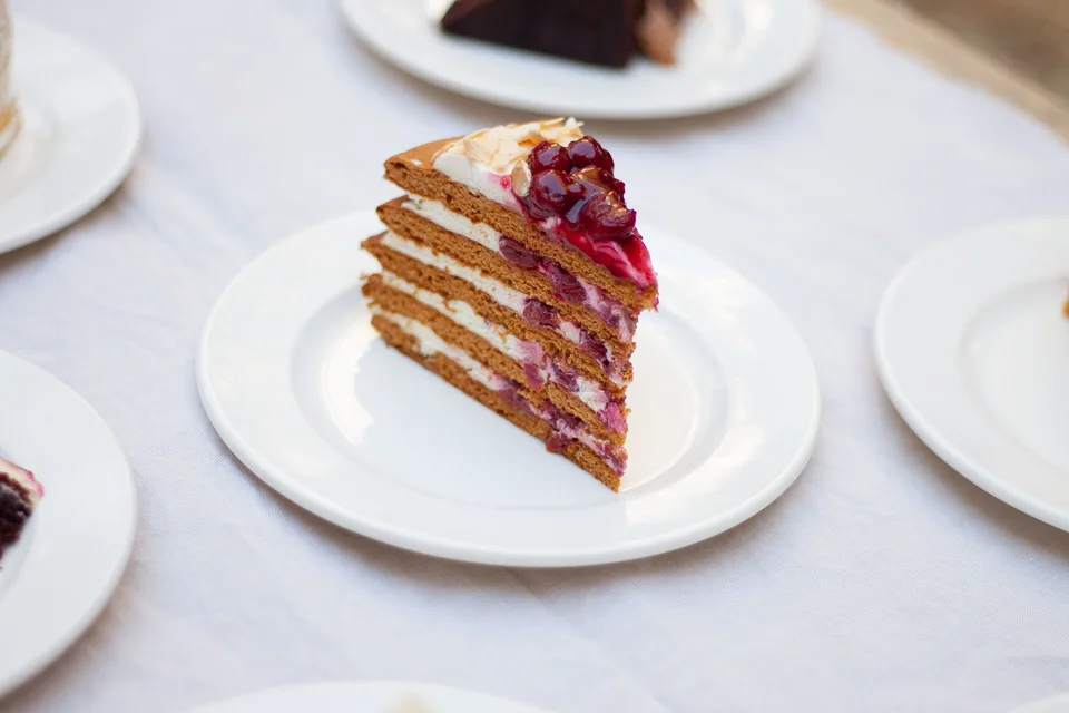 Photo d’illustration : Une part de gâteau à étages garnie de baies, servie sur une assiette blanche