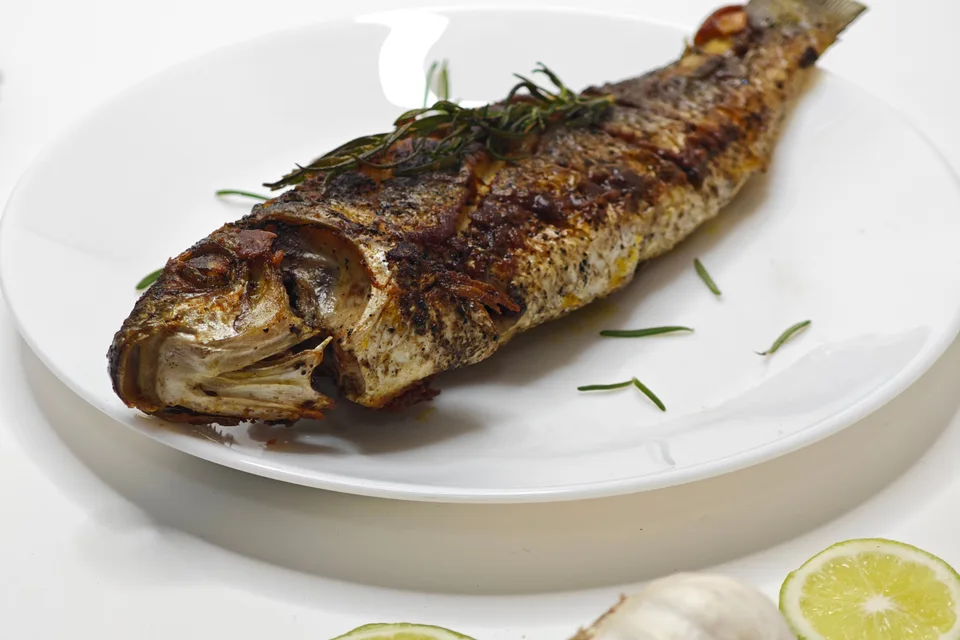 Voorbeeldfoto: Gegrilde vis in zijn geheel op een wit bord